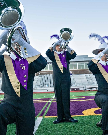 Photo of a marching band posing on a football field.